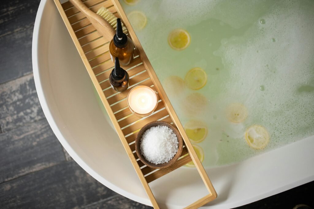 pexels-photo-6620860-6620860 Top view of wooden tray with salt and bottles of cosmetic products placed on white tub with lemon slices on water surface