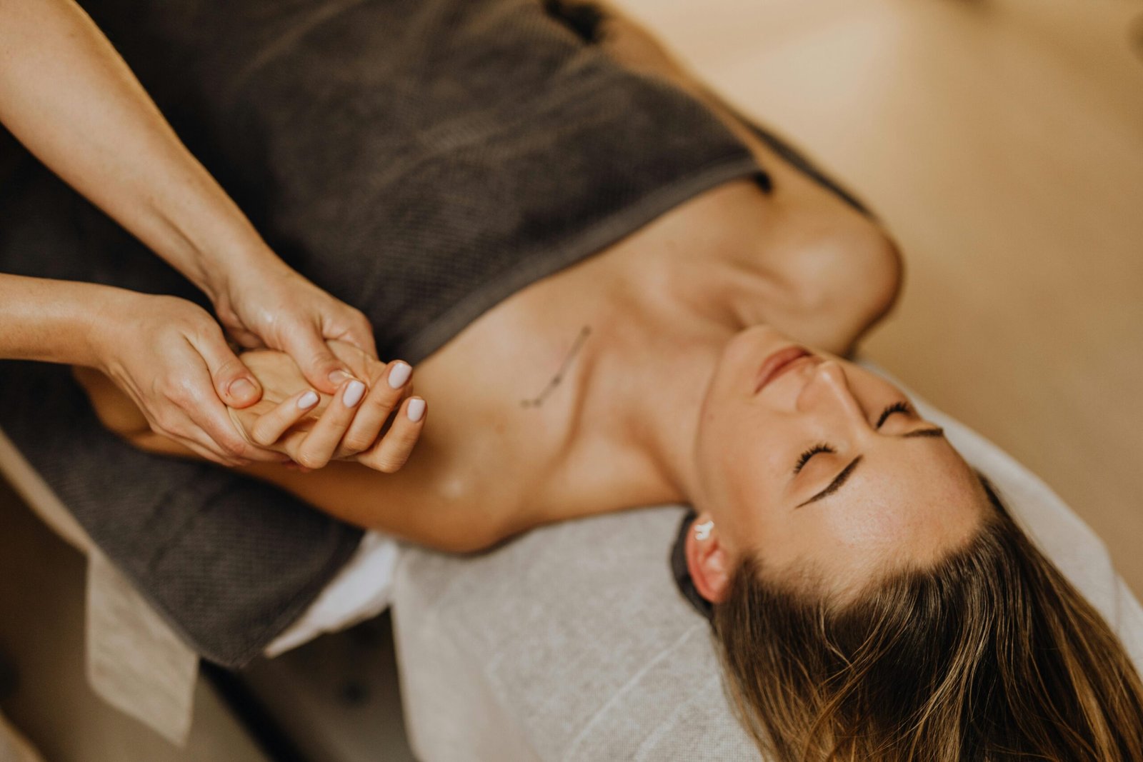 A woman enjoys a relaxing hand massage at a spa, promoting pampering and relaxation.